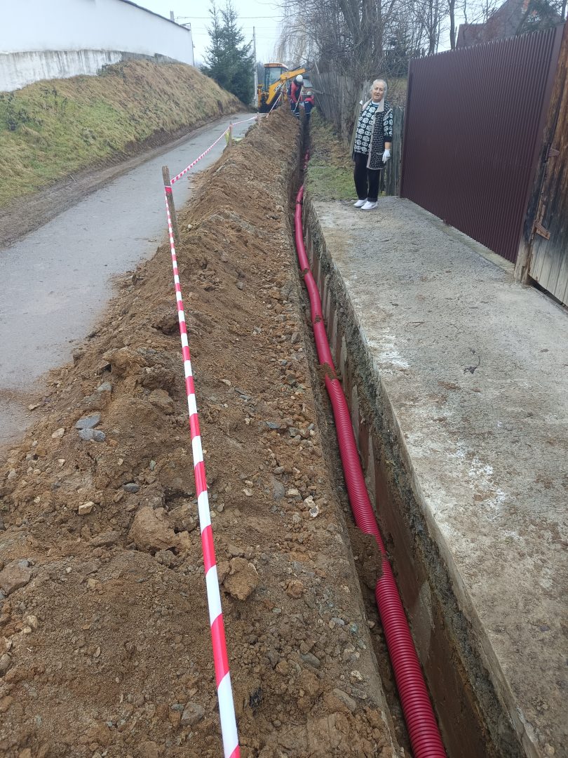 Vedere de ansamblu a lungimii santului de cablu pe langa gard cu buldoexcavator in spate